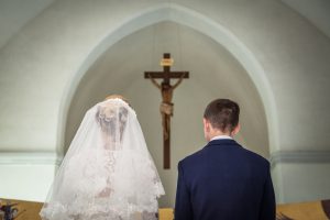Bride and groom stand before crucifix in church 2